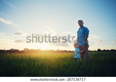 father standing with his son in the park at sunset (intentional sun glare)