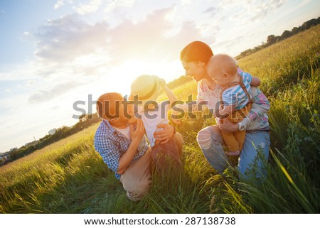 happy young family with kids playing in the park (intentional sun glare, lens focus on son with hat)