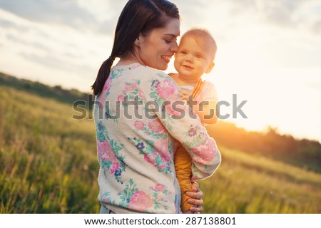 Happy mother with her baby spending time in the park in a sunny day (intentional sun glare)