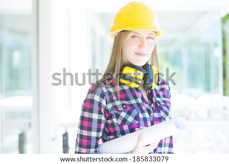 Young architect whit earmuffs, helmet and construction plans