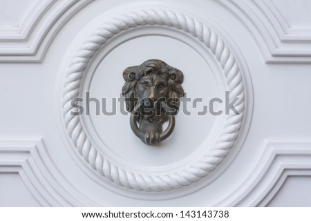 Lion head door knocker on the white door