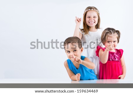 Upset three children with funny hand gestures