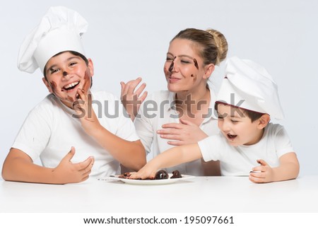 Two little monsters playing with chocolate cake and messing with dessert dish having fun and smiling