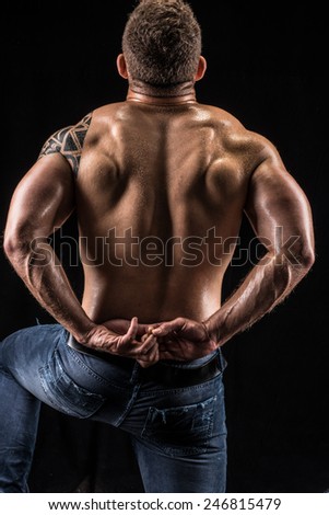Body builder posing to show his back muscles, kneeling