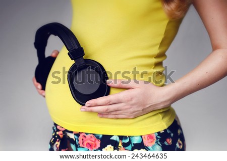 Close up on pregnant belly. Woman expecting a baby. Headphones on her belly. The child listens to music