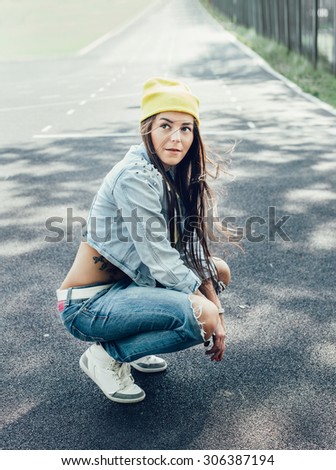 Young woman squatting at the stadium  . Swag teen girls. Outdoor lifestyle portrait girl