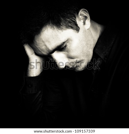 Black and white portrait of a worried and depressed man isolated on black