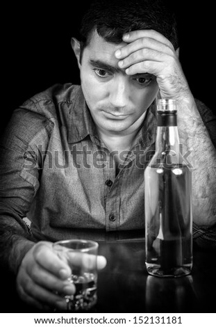 Black and white image of a drunk and sad hispanic man with a black background