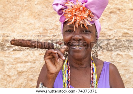 HAVANA-MARCH 28:Woman with typical clothes and a huge cuban cigar on March 28,2011 in Havana.People dress in a way that represents the cuban nationality can be found in the streets of Old Havana