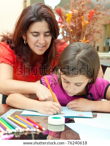 Young latin mother helping her daughter with her art project