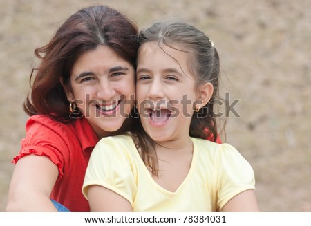 Latin mother and daughter hugging in a park and laughing
