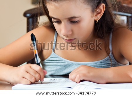 Adorable small latin girl working on her school project at home