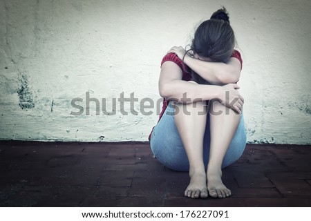 Desaturated grunge image of a very sad adult woman crying