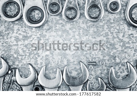 Wrenches and ratchet tools framing a metallic background with space for text