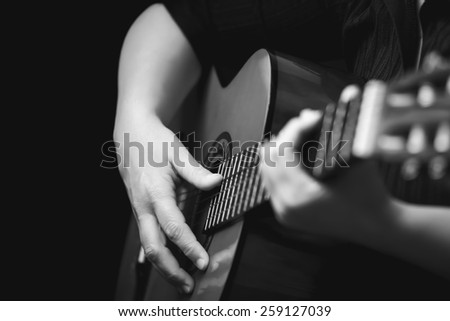 Acoustic guitar detail - Musician hands playing a classic guitar isolated on black