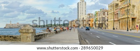 HAVANA,CUBA - MAY 3:2015 : The Malecon seawall in Havana with a view of old buildings, people and old cars