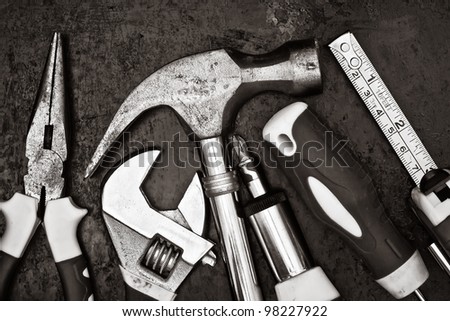 Black and white image of a set of tools on a textured metallic background