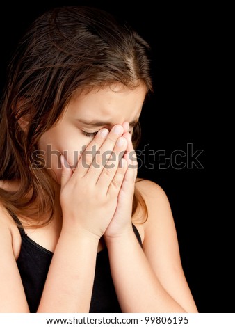 Emotional portrait of a girl crying and hiding her face isolated on black with space for text