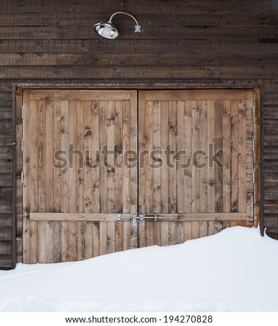 Old wooden barn door with light and snow