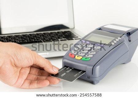 Hand Swiping Credit Card With Laptop In Background