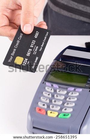 hand holding a credit card with credit card machine