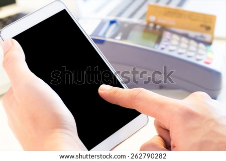 Human Hand Touching Mobile Phone With Credit Card Machine In Background : Selective Focus On Mobile Screen
