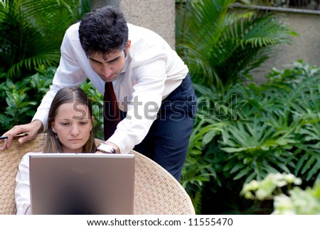 Man and woman in business attire working together outdoors on a laptop