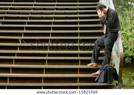 Latin american businessman standing on a set of outdoor stairs holding his head in his hands