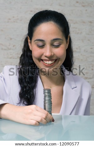 Latin american woman in a business suit with a big smile on her face looking at a big stack of coins