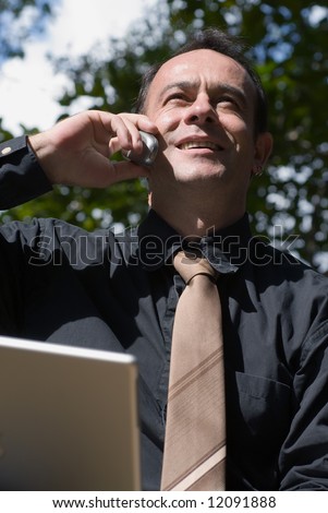 Latin american business man on the phone with his laptop computer open in front of him