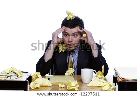 An isolated shot of a businessman sitting at desk covered in crumpled yellow paper.