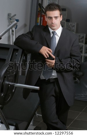 Man in a business suit standing solemnly in a gym