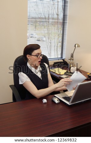 Businesswoman with her mouth open in surprise as she looks at the contents of the envelope in her hand