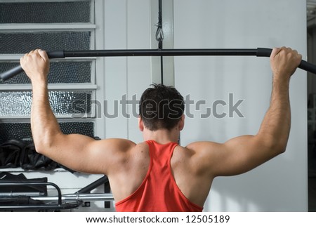 Shot of the muscular back of a male athlete working out on a lat pull-down machine at the gym
