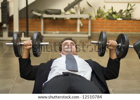 Athletic, young businessman bench pressing weights in a gym