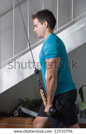 Male athlete doing triceps pulldowns. Arms at full extension