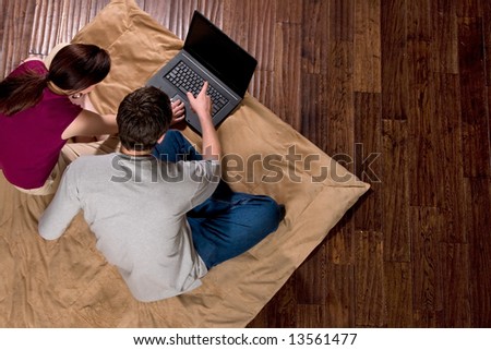 Couple looking at a screen together. He is pointing at the screen. Horizontally framed shot.