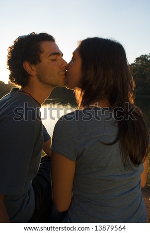 Dark Silhouette of a couple kissing at sunset. Vertically framed photograph.