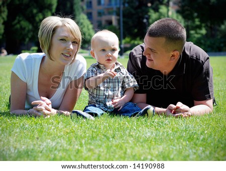 A happy family lying in the grass. The parents on the outside while their son on the inside.- horizontally framed