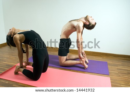 Man and Woman arching their backs and holding their feet as they stretch. Horizontally framed photograph.