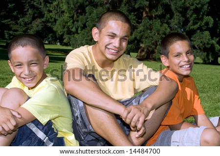 Three brothers sitting in the park smiling. Horizontally framed photograph