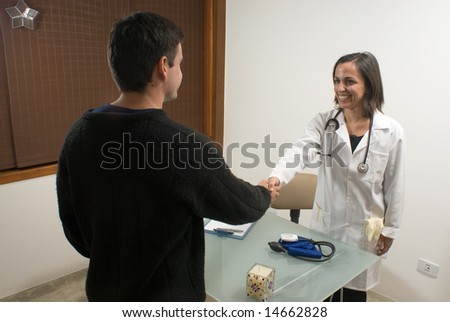 A female doctor is smiling and shaking hands with her patient.  The doctor and the patient are looking at each other.  Horizontally framed photo.