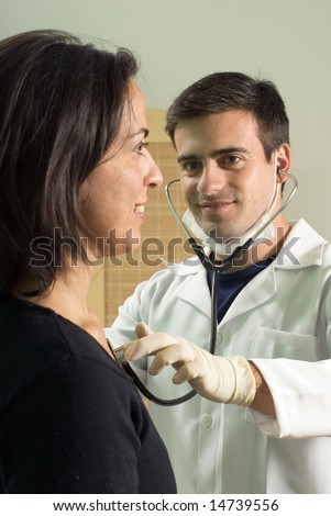 A male doctor, puts his stethoscope onto his patients chest and examines her pulse. - vertically framed