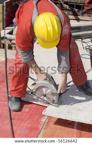 Construction worker bending over to use a rotary saw. Vertically framed photo.
