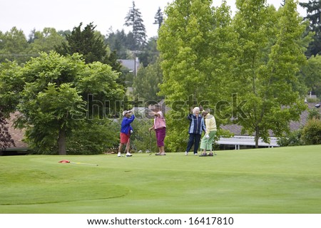 Group of four women slap high five while playing golf. Horizontally framed photo.