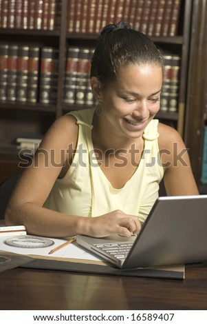 Young woman working on a laptop computer. Vertically framed photograph.