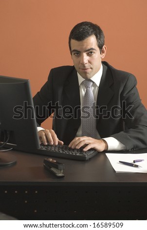 Businessman looking at his laptop computer at his desk. Vertically framed photograph.