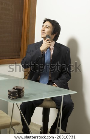 Smiling man in a suit shaving as he sits at a table. Vertically framed photo.