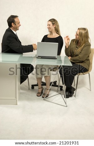 A man and a woman in an office setting. They are smiling and communicating with one another.  Vertically framed shot.