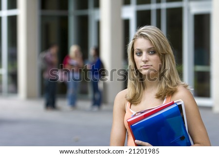 Young student girl holding her books outside of school. Horizontally framed photo.